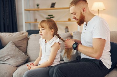 Adam örgüleri örüyor. Baba ve küçük kızı evde birlikteler..