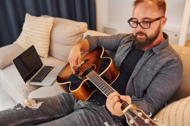 Pratik yaparken iyi vakit geçiriyorum. Gündelik giysiler içinde ve akustik gitarlı bir adam içeride..