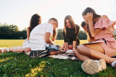 Kadın çizim yapmayı öğretiyor. Bir grup mutlu çocuk gündüz vakti spor sahasında..