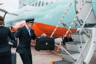 İş üniformalı uçak mürettebatı uçağın yanında birlikte..