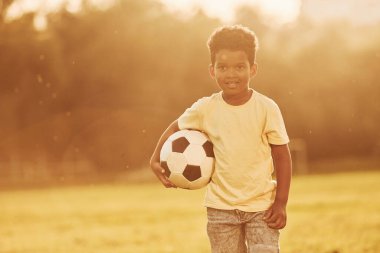 Genç futbolcu. Afrikalı Amerikalı çocuk yaz günlerinde tarlada eğleniyor..