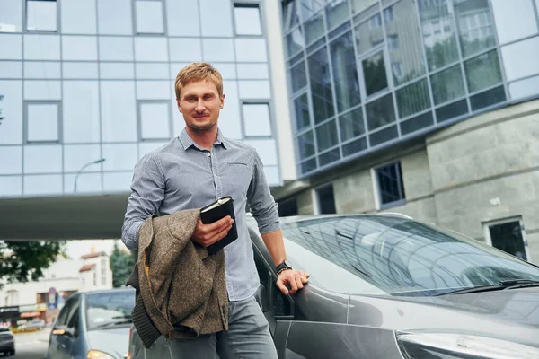 Elinde not defteriyle. Gündüz vakti şehirde gezen bir adam..