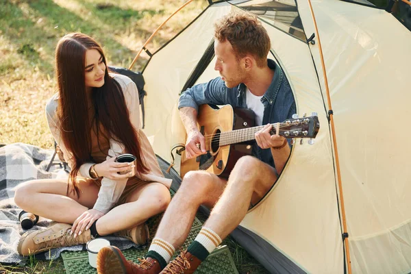 Tipo Tocando Guitarra Pareja Joven Viaja Bosque Durante Día Juntos — Foto de Stock