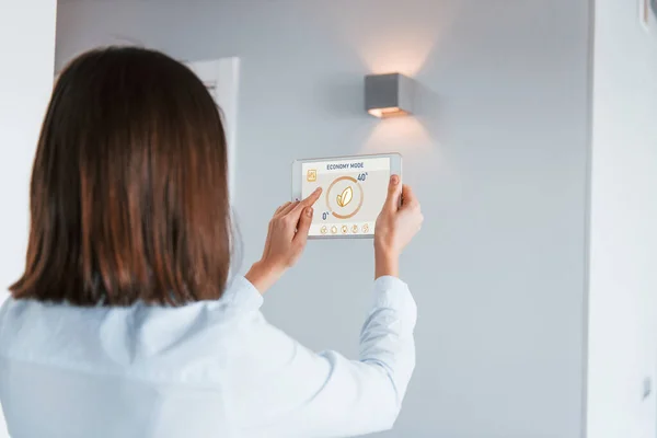 スマートホーム技術を室内で制御している女性の背面図 — ストック写真