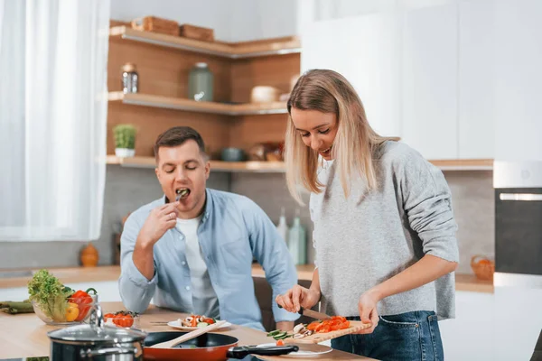 Using vegetables. Couple preparing food at home on the modern kitchen.