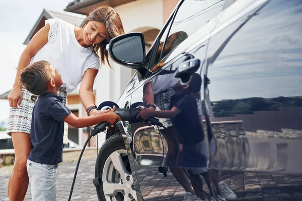 Ricarica Macchina Donna Con Bambino Vicino All Automobile Moderna Durante — Foto Stock