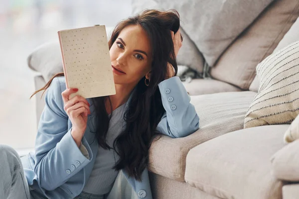 Domestic room. European woman in fashionable stylish clothes is posing indoors.