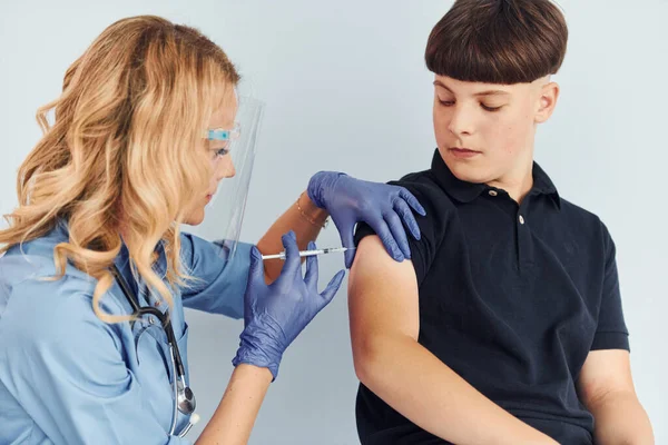 穿制服的医生给穿黑衬衫的男孩注射疫苗 — 图库照片