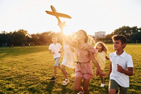 玩玩具飞机 一群快乐的孩子白天在运动场上玩耍 — 图库照片