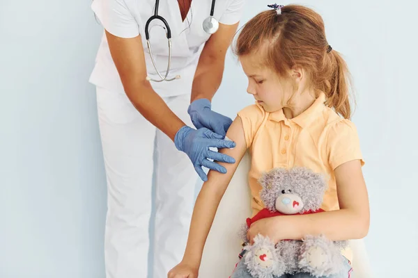 Cute little girl. Doctor in uniform making vaccination to the patient.