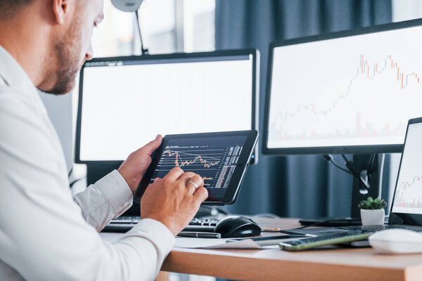 Modern technologies. Young businessman in formal clothes is in office with multiple screens.