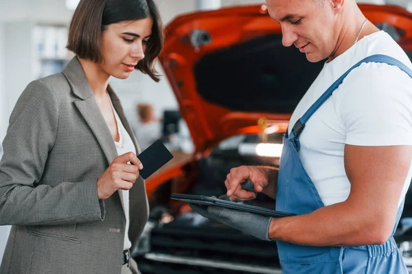 Paying Service Man Repairing Woman Automobile Indoors — Stock Photo, Image