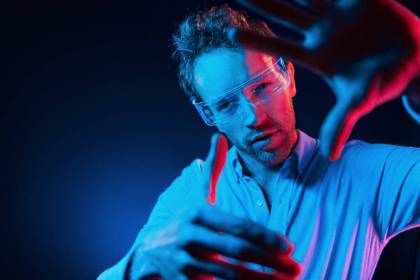 Концепция виртуальной реальности. Неоновое освещение. Молодой европеец в темной студии..