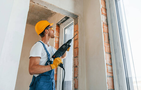 In hard hat. Young man working in uniform at construction at daytime.