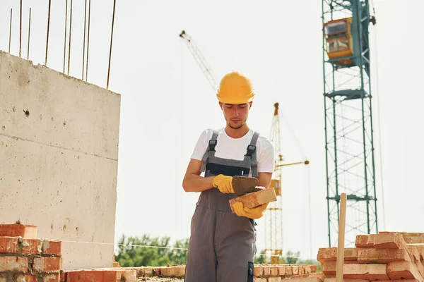 Jovem Trabalhador Construção Uniforme Está Ocupado Edifício Inacabado — Fotografia de Stock