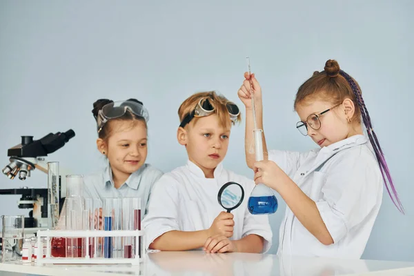 Παιδιά Λευκά Παλτά Παίζουν Έναν Επιστήμονα Στο Εργαστήριο Χρησιμοποιώντας Εξοπλισμό — Φωτογραφία Αρχείου