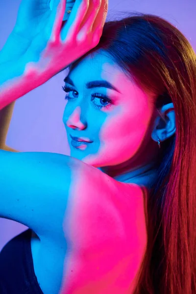 Tarafsız yüz ifadesi. Stüdyoda neon ışığıyla duran şık bir genç kadın..