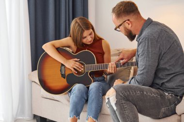 Özel ders. Gitar öğretmeni enstrümanı genç bir kadına nasıl çalacağını gösteriyor..