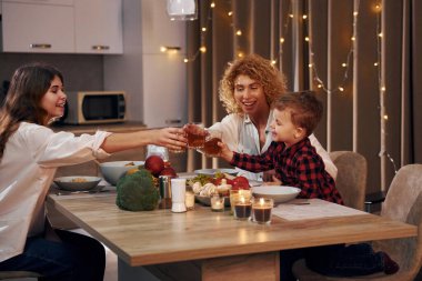 Hafta sonunu birlikte geçirmek. Anne, kız ve oğlanın mutlu ailesi akşam vakti mutfaktadır..