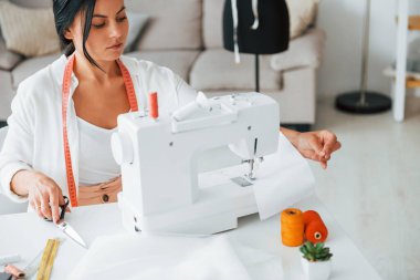 Dikiş makinesiyle çalışıyor. Terzi odasında, farklı kıyafetlerle..