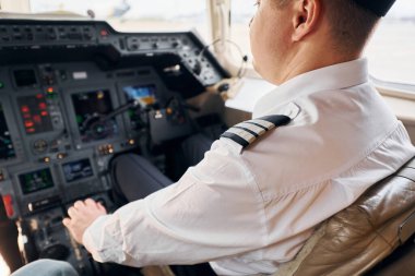 Sakin atmosfer. Resmi kıyafetli pilot kokpitte oturur ve uçağı kontrol eder..
