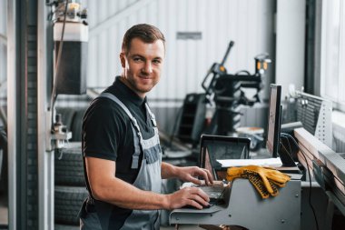 Gündüz vakti. Üniformalı adam otomobil servisinde çalışıyor..