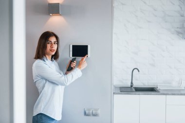 Bir dokunuşla evi kontrol ediyor. Genç bayan gündüz vakti akıllı ev odasında..