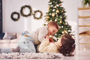 Uzanmak ve oynamak. Küçük kız ve erkek kardeş noel süsleme odasında beraberler..