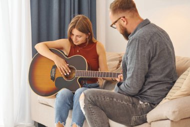 Gitar öğretmeni enstrümanı genç bir kadına nasıl çalacağını gösteriyor..