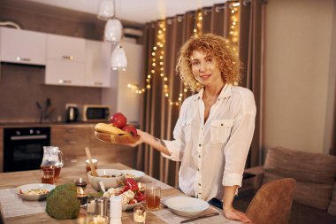 Akşam vakti beyaz gömlekli kadın mutfakta dikiliyor..