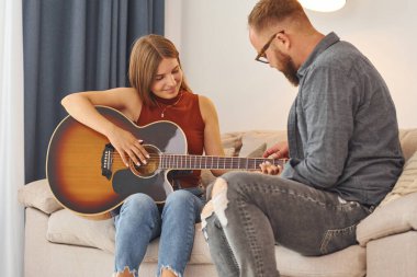 Gitar öğretmeni enstrümanı genç bir kadına nasıl çalacağını gösteriyor..