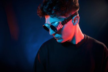 Siyah arka plana karşı. Neon ışıkları. Genç Avrupalı adam karanlık stüdyoda..