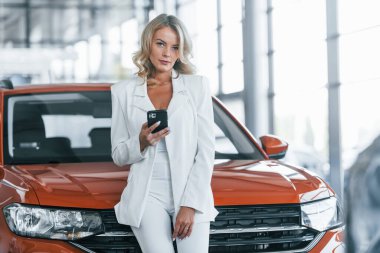 Arabaya yaslan. Resmi giyinmiş bir kadın otosalon 'da içeride..