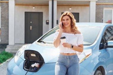 Şarjın bitmesini bekliyorum. Gündüz vakti elektro-mobil arabasıyla gezen genç bir kadın..