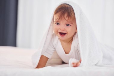Beyaz havluyla. Şirin küçük bebek evdeki odada..