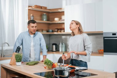 Birbirleriyle tartışıyorlardı. Modern mutfakta yemek hazırlayan bir çift..