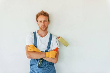 Duvarları boyuyorum. Gündüz vakti inşaatta üniformalı genç bir adam çalışıyor..