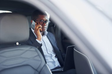 Yolcu arka koltukta. Siyah takım elbiseli genç Afro-Amerikan işadamı otomobilde..