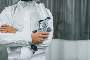 Koruyucu beyaz üniformalı. Adam otomobil servisinde çalışıyor..