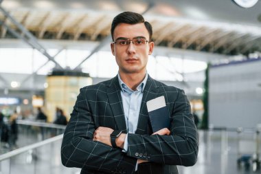 Kollarını kavuşturarak. Resmi kıyafetli genç işadamı gündüz vakti havaalanında..