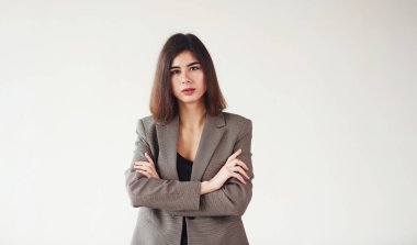 Resmi giyinmiş genç bir kadın stüdyoda beyaz arka planda duruyor..