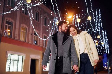 El ele tutuşarak. Mutlu genç çift sokakta yeni yılı kutluyor..