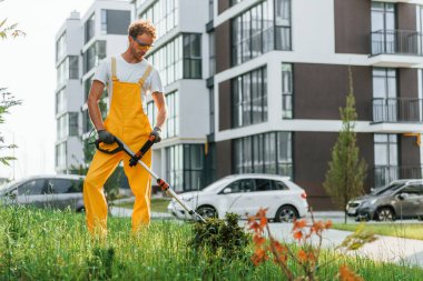 Bir kişi. Bahçede çimleri çim biçen bir adam var..
