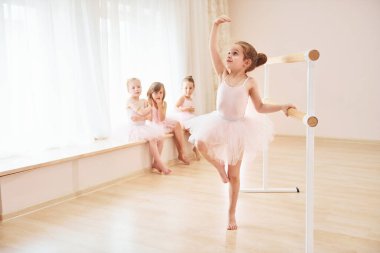 Pembe üniformalı küçük balerinler gösteriye hazırlanıyor..