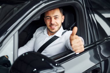 Başarılı bir adam. Beyaz gömlekli genç adam modern bir otomobilin içinde oturuyor..