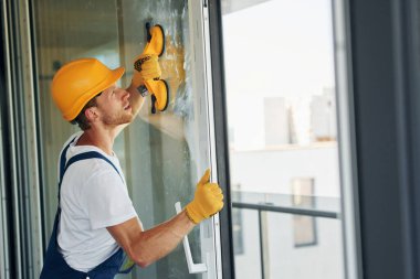 Koruyucu şapkayla. Gündüz vakti inşaatta üniformalı genç bir adam çalışıyor..
