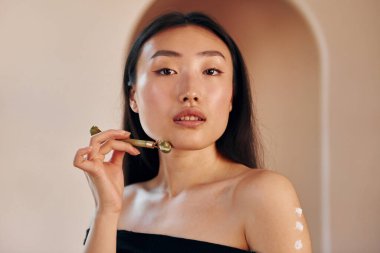 Deri temizleme aleti kullanıyor. Genç ciddi Asyalı kadın içeride duruyor..