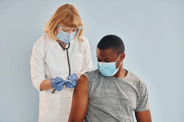 资深医生在医院为年轻的非洲裔美国人注射疫苗 — 图库照片