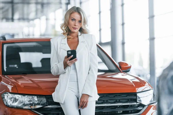 Arabaya yaslan. Resmi giyinmiş bir kadın otosalon 'da içeride..