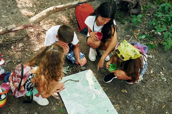 坐在地上 孩子们带着旅行器材在森林里散步 — 图库照片